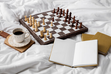 Wall Mural - Chess board with books and cup of coffee on bed