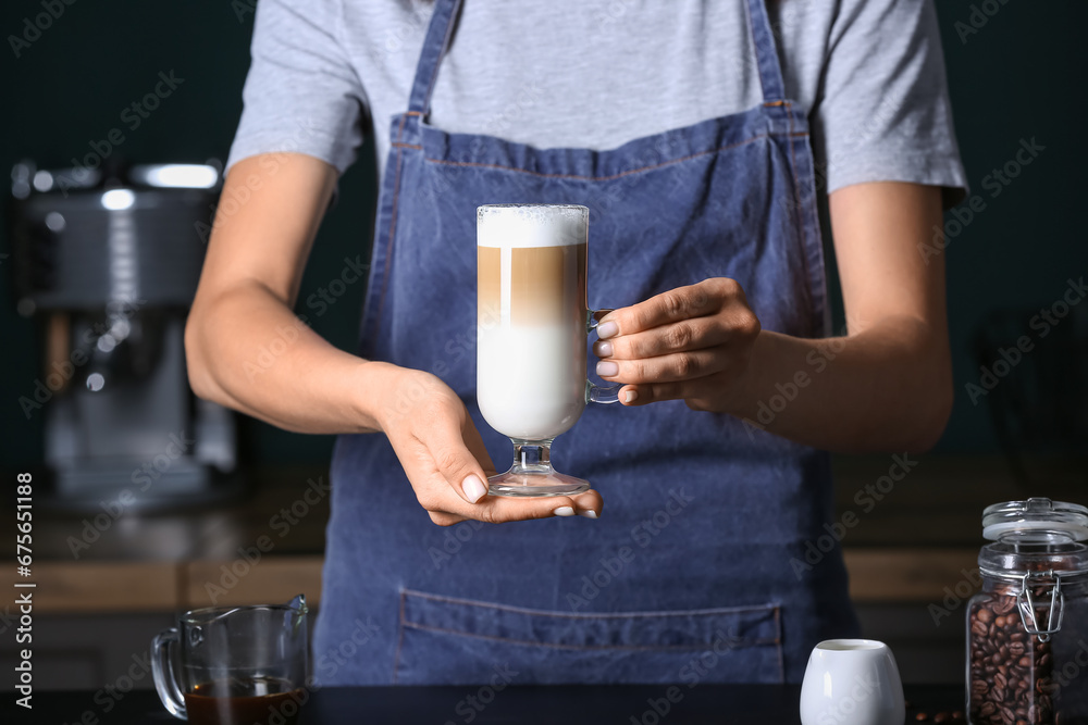 Barista holding glass of tasty latte in cafe