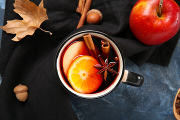 Wall Mural - Cup of hot mulled wine with orange and apple on blue background