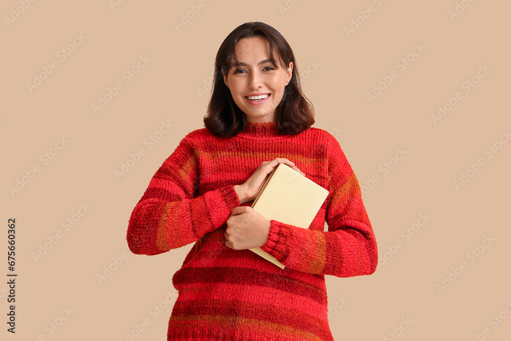 Young woman in red sweater with book on beige background