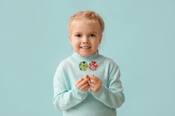 Wall Mural - Cute little girl with sweet lollipops on blue background