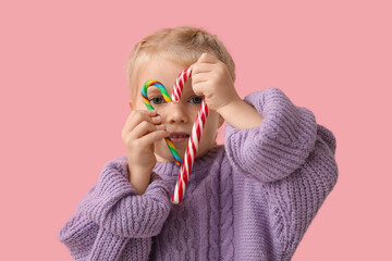 Wall Mural - Cute little girl with tasty candy canes on pink background