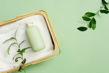 Rattan Basket Holds Towels And Unlabeled Shower Gel Bottles On A Pastel Green Background. Green Tea Extract In Shower Gel Helps Brighten Skin And Improve Back Acne.