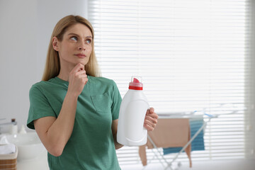 Wall Mural - Thoughtful woman holding fabric softener in bathroom, space for text