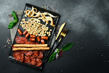Wall Mural - Antipasto, Appetizers for beer: salami, cheese, nuts and sausages. On a dark background, close-up.