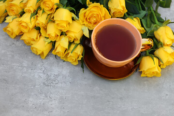 Canvas Print - Cup of tea and beautiful yellow roses on light table, above view. Space for text