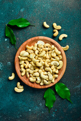 Wall Mural - Cashew nut in a wooden bowl. Healthy snacks. On a dark background.