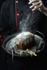 Wall Mural - Homemade black square bran bread in hands. Fresh bread on a black background.