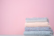 Stack of winter knitted sweaters on a pink background. Change of season. Conscious consumption. Environmental friendliness and sustainable fashion. space for text.