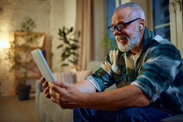 side view portrait of mature man in glasses sitting on couch in living room and watching movie in ta