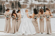 The bride and her bridesmaids pose, holding bouquets behind them, back view. Winter wedding