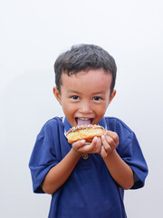 Wall Mural - cute little asian boy eating donut isolated on white background