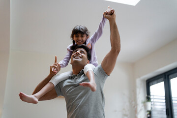 Wall Mural - Father carrying daughter on shoulders at home