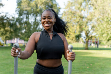 Wall Mural - Smiling young woman exercising in outdoor gym