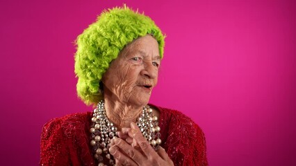 Wall Mural - Surprised, happy, funny crazy elderly mature woman with no teeth, 80s, acting shy isolated on pink background. Concept of elderly shy person.