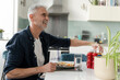 Smiling mature man eating breakfast at home