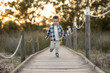 Niño con camisa de cuadros paseando sobre un puente rodeado de naturaleza