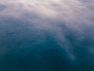 Aerial view of a sunrise sea with a blanket of morning fog and morning sunbeams shining through