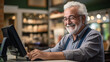 Portrait of senior man using computer in coffee shop. Cheerful mature man working on computer at cafe.