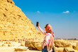 Woman tourist takes photographs of the Pyramid of Khafre.