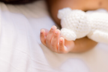 Wall Mural - Close-up of newborn fingers and a stuffed white knitted bear