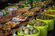 Detail shot of a street market stall full of different types of olives, gherkins, chillies, pickles and spring onions in handmade earthenware containers.
