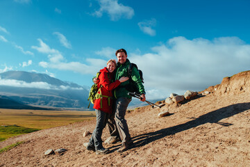 Sticker - Happy young couple posing in the mountains on blue sky background