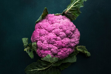 Wall Mural - Fresh organic purple cauliflower cabbage with leaves on old rustic green table background, top view