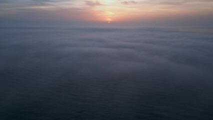 Wall Mural - Aerial view of a sunrise sea with a blanket of morning fog and morning sunbeams shining through