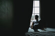 © Sevendeman - Lonely single man sit and rest alone in dark bedroom with light from curtain.