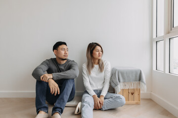 Boring and tired faces of asian lover sit on the floor of empty room.