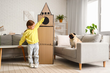 Sticker - Little girl playing with cardboard rocket and pug dog at home