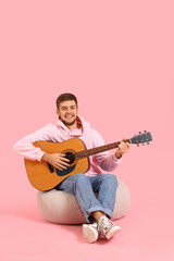 Canvas Print - Young bearded man playing guitar on pink background