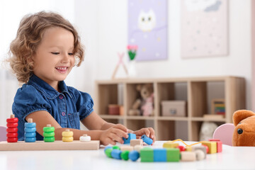 Poster - Motor skills development. Little girl playing with stacking and counting game at table indoors