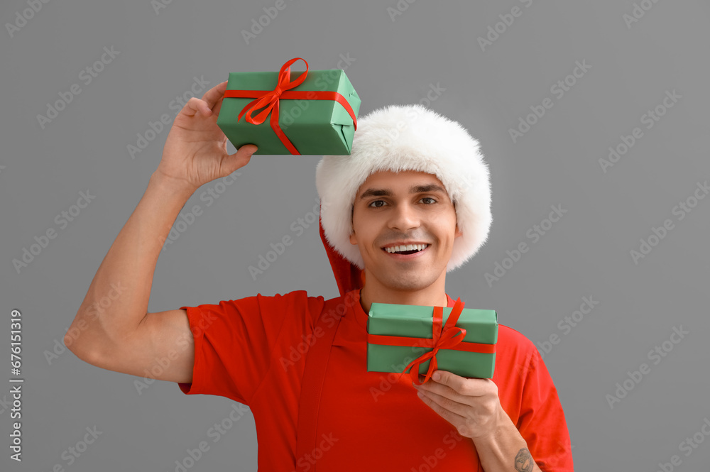 Santa Claus with gift boxes on grey background