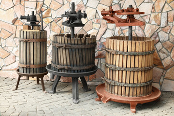 Wall Mural - Metal winepresses in wooden barrels near stone wall outdoors