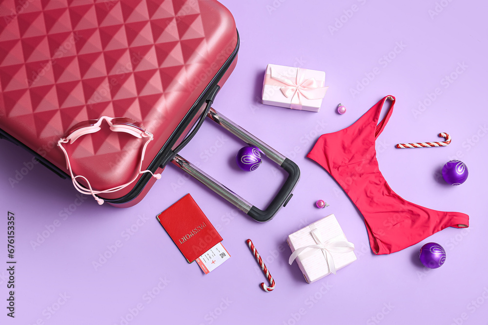Composition with suitcase, beach accessories, Christmas gifts and decorations on color background
