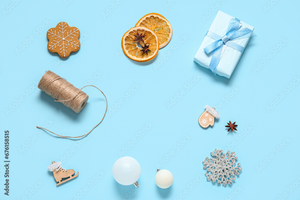 Gift box with tasty Christmas cookie and decor on blue background