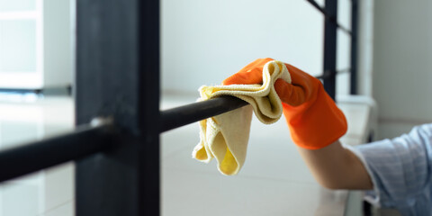 Hands in blue rubber gloves holding microfiber cleaning cloth make cleaning and disinfection for good hygiene of a stair railing