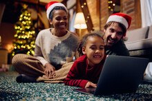 Happy Multiracial Family Surfing The Net On Laptop At Home On Christmas.