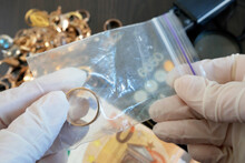Pawnshop Worker Packing A Gold Wedding Ring On Many Golden And Silver Jewelleries And Jewelry Scales Background, Top View