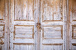 Wooden closed discolored empty door locked with rusty padlock background texture