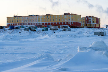 Wall Mural - View of a small arctic village on the coast of the frozen sea. Winter arctic landscape. Multi-colored residential buildings. Settlement in the far north. Cold weather. Tavayvaam, Chukotka, Russia.