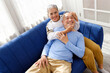 © artitwpd - Portrait of happy Asian senior couple living together, hug, touching and embracing with a smile on the sofa in the living room. Retirement living together at home.