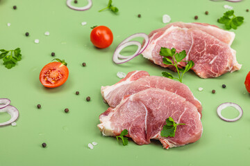 Wall Mural - Pieces of pork meat with parsley, purple onion rings and tomato, raw fresh steaks concept