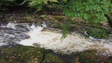 The River Tavy Flowing Over Boulders And Between Rocks In The River Causing The Water To Have A Strong Current And Splash And Foam