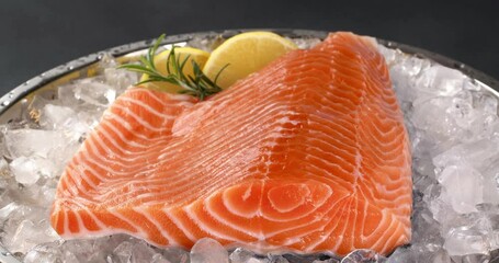 Canvas Print - Salmon on a tray with ice on a dark background. Close-up footage on the rotating table.