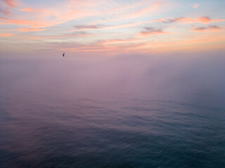 Wall Mural - Aerial view of a sunrise sea with a blanket of morning fog and morning sunbeams shining through