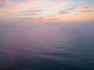 Wall Mural - Aerial view of a sunrise sea with a blanket of morning fog and morning sunbeams shining through