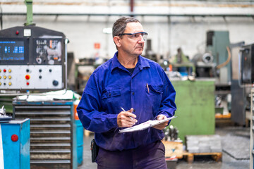 Factory worker operator in the numerical control sector making a report to send to suppliers, industrial factory